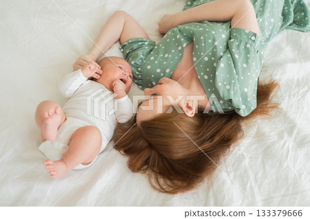 Happy family at home. Mother holding little baby toddler child feeding milk from bottle. Newborn Infant baby girl sucking eating drinking milk. Mom of breast feeding baby. Motherhood happy child 133379666