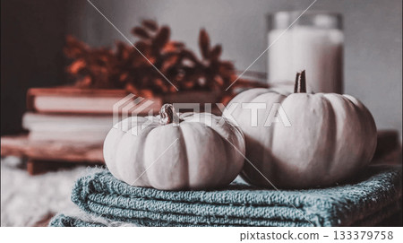 Autumn still life with pumpkins and flowers. A cozy autumn still life features white pumpkins, fall flowers, candles, and a soft blanket  This is AI-generated item 133379758