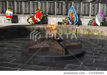 Solemn memorial scene featuring an eternal flame atop a star shaped granite base 133380461