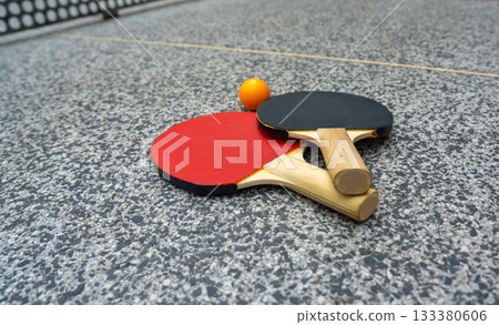 Rackets for table tennis in park close up. Red black ping pong table tennis paddles and yellow ball 133380606