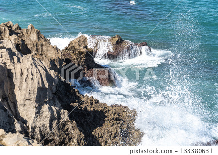 Waves of the Atlantic Ocean crash against sharp volcanic coastal rocks on a sunny day Waves of the Atlantic Ocean crash against sharp volcanic coastal rocks on a sunny day 133380631