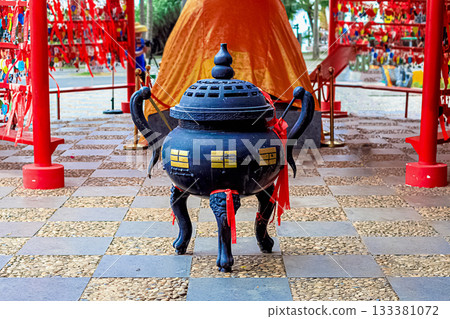 A large bronze vessel with red ribbons and gold patterns stands in front of the temple. A large bronze vessel with red ribbons and gold patterns stands in front of the temple. 133381072