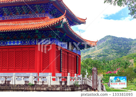 A traditional Chinese building with red walls, carved doors, and a curved roof. 133381093