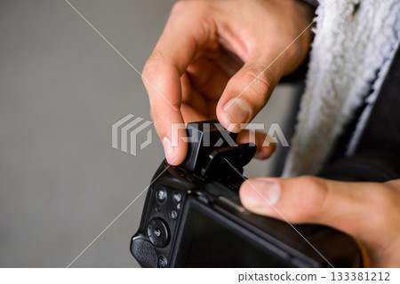 Photographer inserts battery into professional camera outdoor while having a photoshoot. Professional artist has run out of battery life in camera while shooting pictures Photographer inserts battery into professional camera outdoor while having a photoshoot. Professional artist has run out of battery life in camera while shooting pictures 133381212