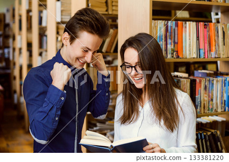 Smiling male and female students looking to the book happy to find necessary information for report Smiling male and female students looking to the book happy to find necessary information for report 133381220