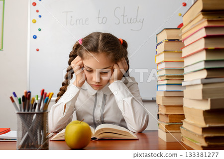 Bored elementary learner reading a book. Concept of studying, reading 133381277
