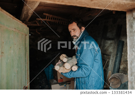 Despaired man carrying firewood for heating at home. 133381434