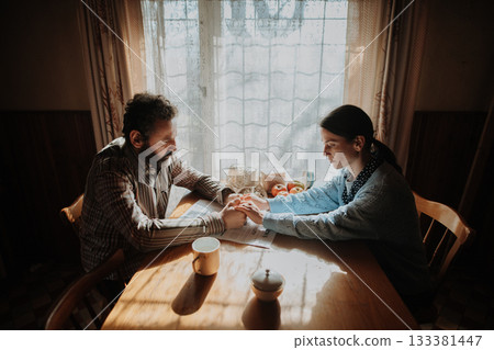 Portrait of poor mature couple sitting at table, fearing the future. Portrait of poor mature couple sitting at table, fearing the future. 133381447