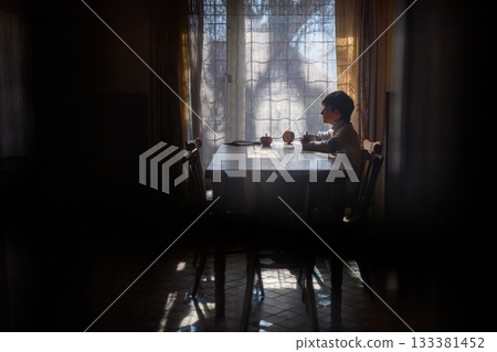 Poor sad orphan girl looking out of window. 133381452