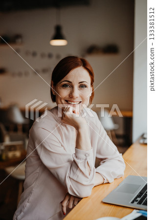 A portrait of woman working remotely from coffee shop, using laptop. A portrait of woman working remotely from coffee shop, using laptop. 133381512