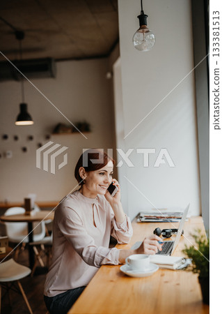 A portrait of woman working remotely from coffee shop, making phone call. A portrait of woman working remotely from coffee shop, making phone call. 133381513