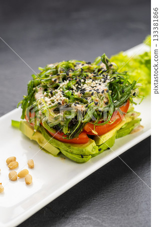 Layered avocado and seaweed salad with sesame on a modern plate 133381866