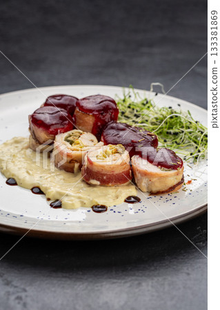 Chicken bacon roulade with berry sauce and creamy puree, plated with microgreens 133381869