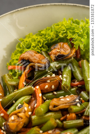 Mussel and green bean salad with sesame in a ceramic bowl on dark stone Mussel and green bean salad with sesame in a ceramic bowl on dark stone 133381872