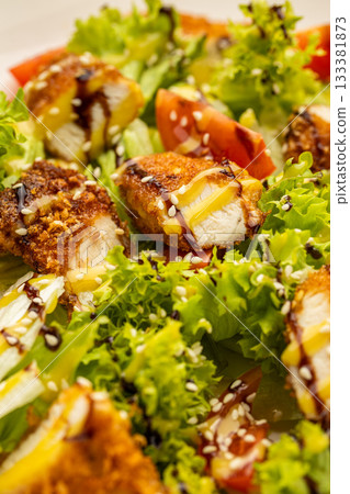 Crispy chicken salad with lettuce, tomatoes, sesame and dressing on plate Crispy chicken salad with lettuce, tomatoes, sesame and dressing on plate 133381873