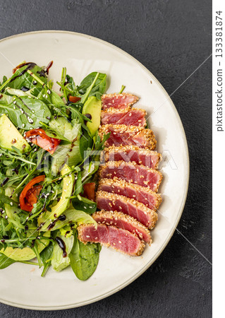 Seared tuna salad with avocado, arugula and sesame on plate, healthy gourmet lunch 133381874