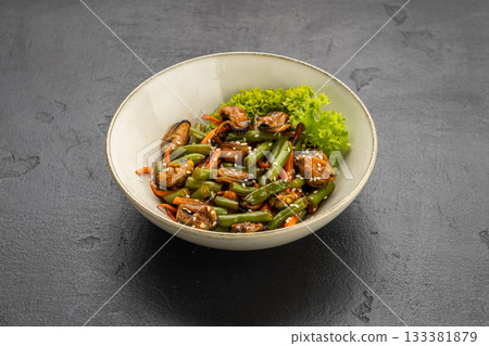 Mussel and green bean salad with sesame in a ceramic bowl on dark stone 133381879