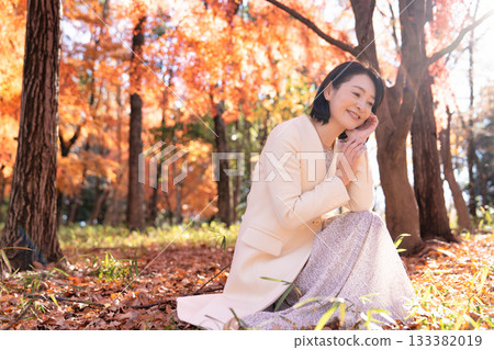 一位中年婦女在秋葉滿布的公園漫步 133382019