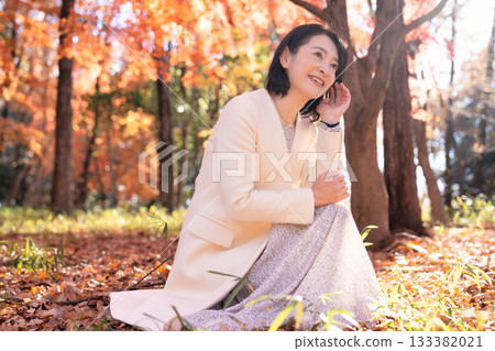 一位中年婦女在秋葉滿布的公園漫步 133382021