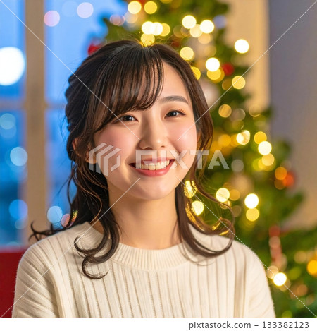A woman smiling gently in front of a decorated tree 133382123