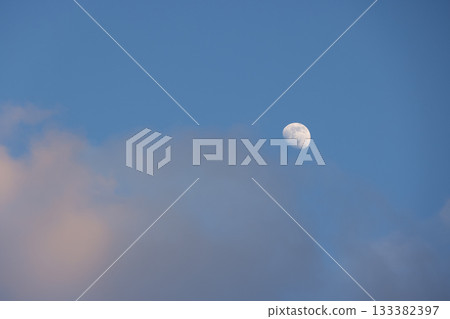 Gibbous moon appearing in a blue sky with clouds Gibbous moon appearing in a blue sky with clouds 133382397