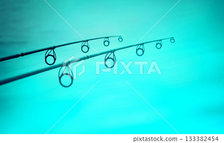 Two fishing rods over blue lake water Two fishing rods over blue lake water 133382454