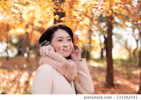 一位中年婦女在秋葉滿布的公園漫步 133382541
