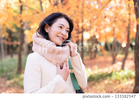 一位中年婦女在秋葉滿布的公園漫步 133382547