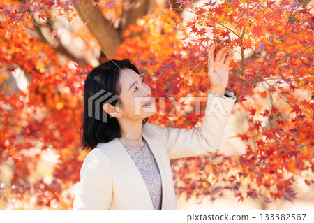 A middle-aged woman strolling through a park with autumn leaves A middle-aged woman strolling through a park with autumn leaves 133382567