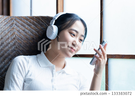 年輕女子戴著耳機在智慧型手機上聽音樂 133383072