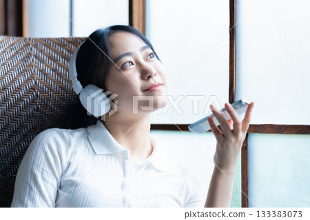 年輕女子戴著耳機在智慧型手機上聽音樂 133383073