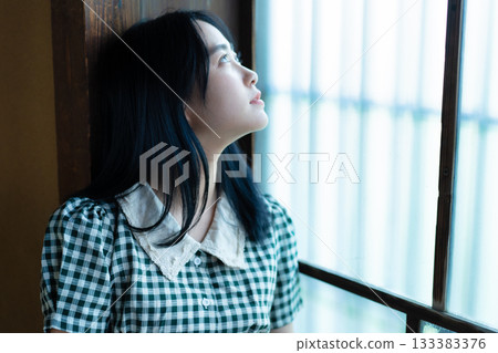 A high school girl relaxing by the window in a Japanese-style room A high school girl relaxing by the window in a Japanese-style room 133383376