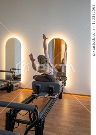 Two women in sunrise stretch with awareness, women reach and move in sunrise reformer flow Two women in sunrise stretch with awareness, women reach and move in sunrise reformer flow 133383562