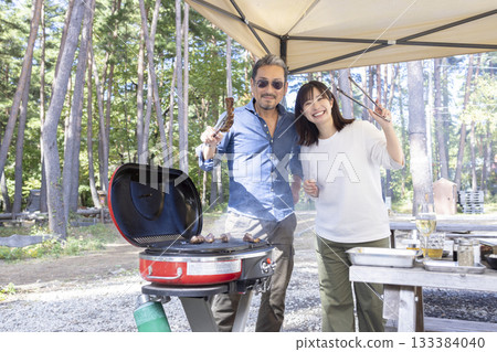 Family having a BBQ at a campsite Family having a BBQ at a campsite 133384040