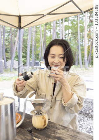A woman having a BBQ at a campsite A woman having a BBQ at a campsite 133384588