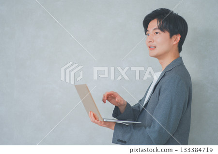 A man in office casual clothes holding a laptop 133384719