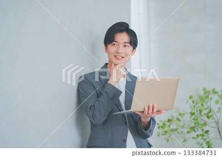 一名身穿商務休閒裝的男子手持筆記型電腦 一名身穿商務休閒裝的男子手持筆記型電腦 133384731