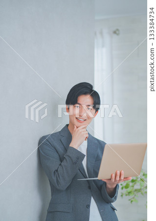 一名身穿商務休閒裝的男子手持筆記型電腦 133384734
