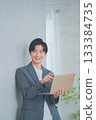 A man in office casual clothes holding a laptop 133384735