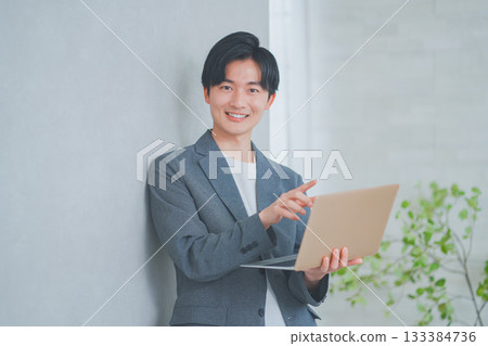 一名身穿商務休閒裝的男子手持筆記型電腦 133384736