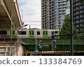 Train passing over a bridge in a modern Japanese city 133384769