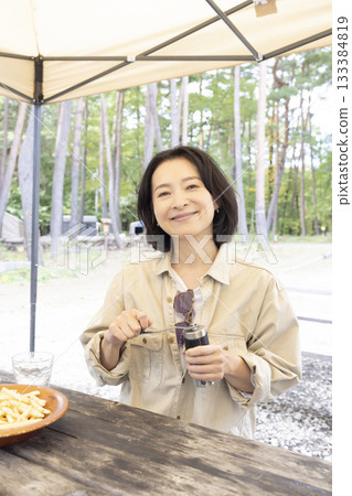 A woman having a BBQ at a campsite A woman having a BBQ at a campsite 133384819