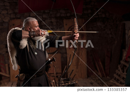 A fierce Viking warrior with long, braided hair and a white beard, dressed in traditional armor with fur, aiming a bow weapon, showcasing strength, heritage, and combat readiness 133385357