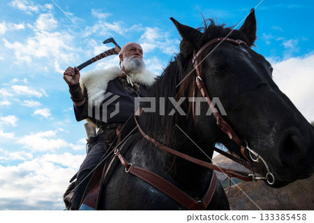 A fierce Viking warrior on horseback, wielding an axe, stands against a dramatic sunset sky with clouds and mountains, embodying strength, exploration, and ancient legend. A fierce Viking warrior on horseback, wielding an axe, stands against a dramatic sunset sky with clouds and mountains, embodying strength, exploration, and ancient legend. 133385458