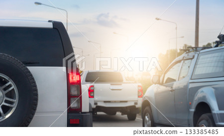 Rear side family car white color SUV model. Many cars driving on the road with sunlight on the sky. 133385485