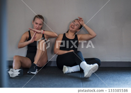 Friends enjoying a break after an intense workout session at the gym in a modern fitness studio in the afternoon 133385586