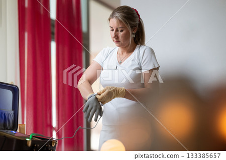 Professional female therapist wearing gloves and preparing equipment while a man lies on a massage table covered with a towel. Spa and wellness treatment concept highlighting relaxation, health care Professional female therapist wearing gloves and preparing equipment while a man lies on a massage table covered with a towel. Spa and wellness treatment concept highlighting relaxation, health care 133385657