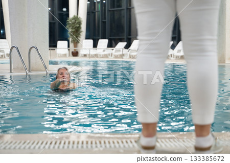 Instructor leading aquatic fitness training for group senior women in a swimming pool. Concept of health, exercise, wellness, water therapy, and active aging lifestyle 133385672