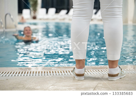 Instructor leading aquatic fitness training for group senior women in a swimming pool. Concept of health, exercise, wellness, water therapy, and active aging lifestyle 133385683