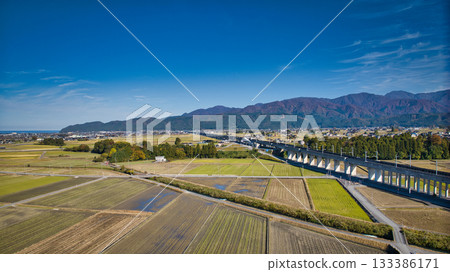 A view of the Hokuriku Shinkansen line near the viaduct running through Nyuzen Town, Toyama Prefecture, with the Northern Alps in the background 133386171